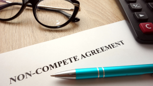 A non-compete agreement document on a desk with a teal pen, glasses, and a calculator nearby, ready for signing