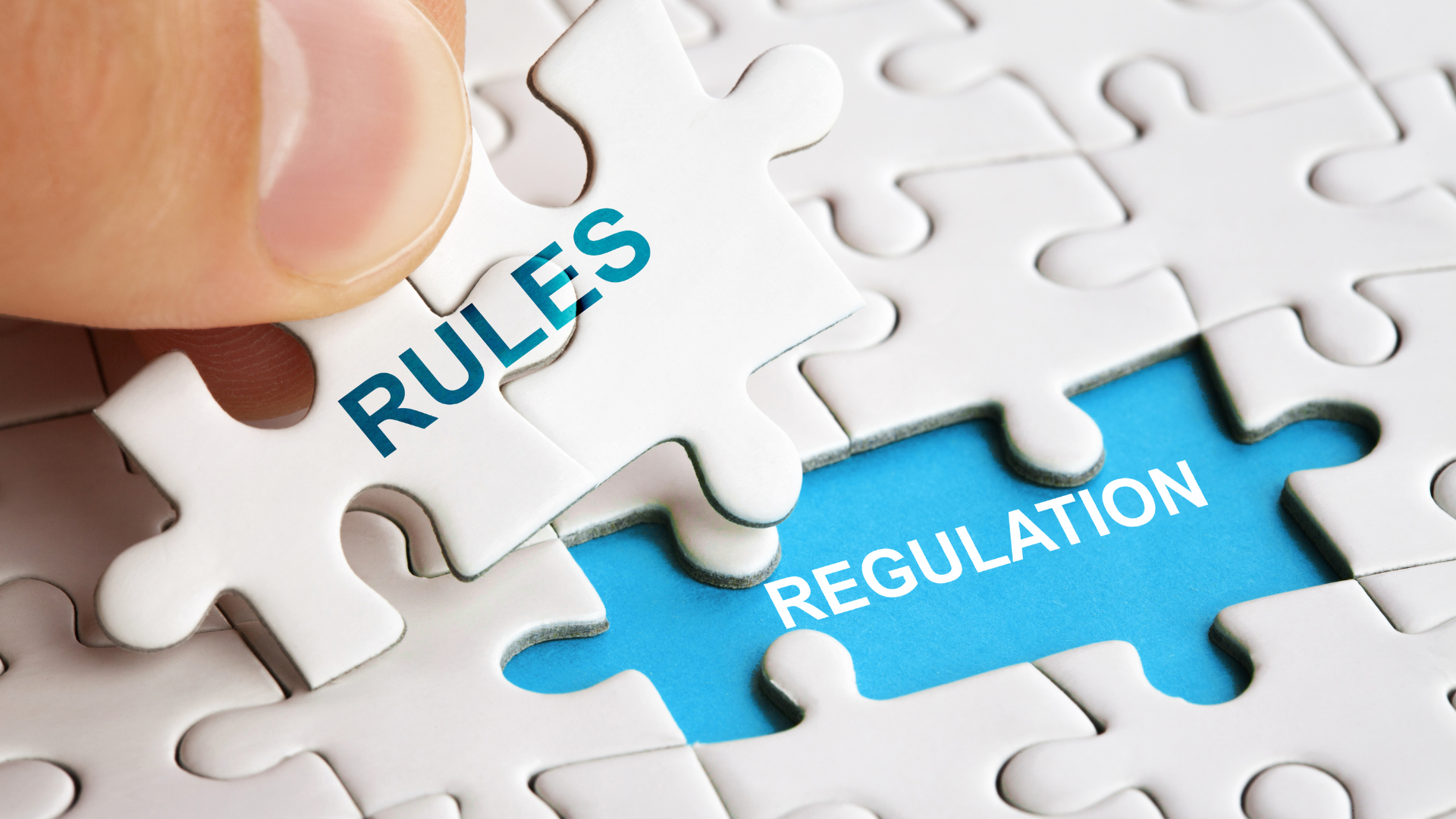 Puzzle piece labeled 'RULES' being placed into a white jigsaw on a blue background that reads 'REGULATION'.