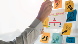 Person placing colorful sticky notes on a glass board for project planning and teamwork
