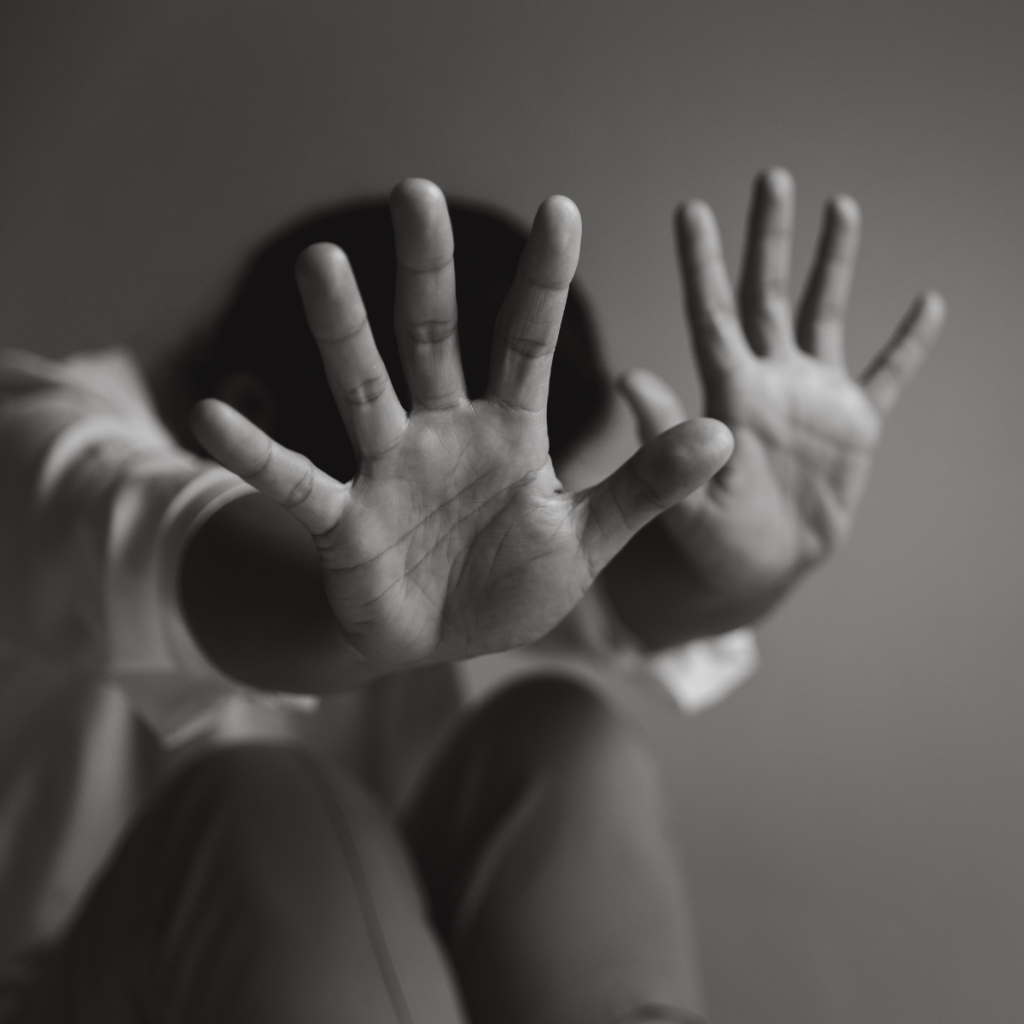 Two outstretched hands reaching toward the camera in a stop gesture, black-and-white photo